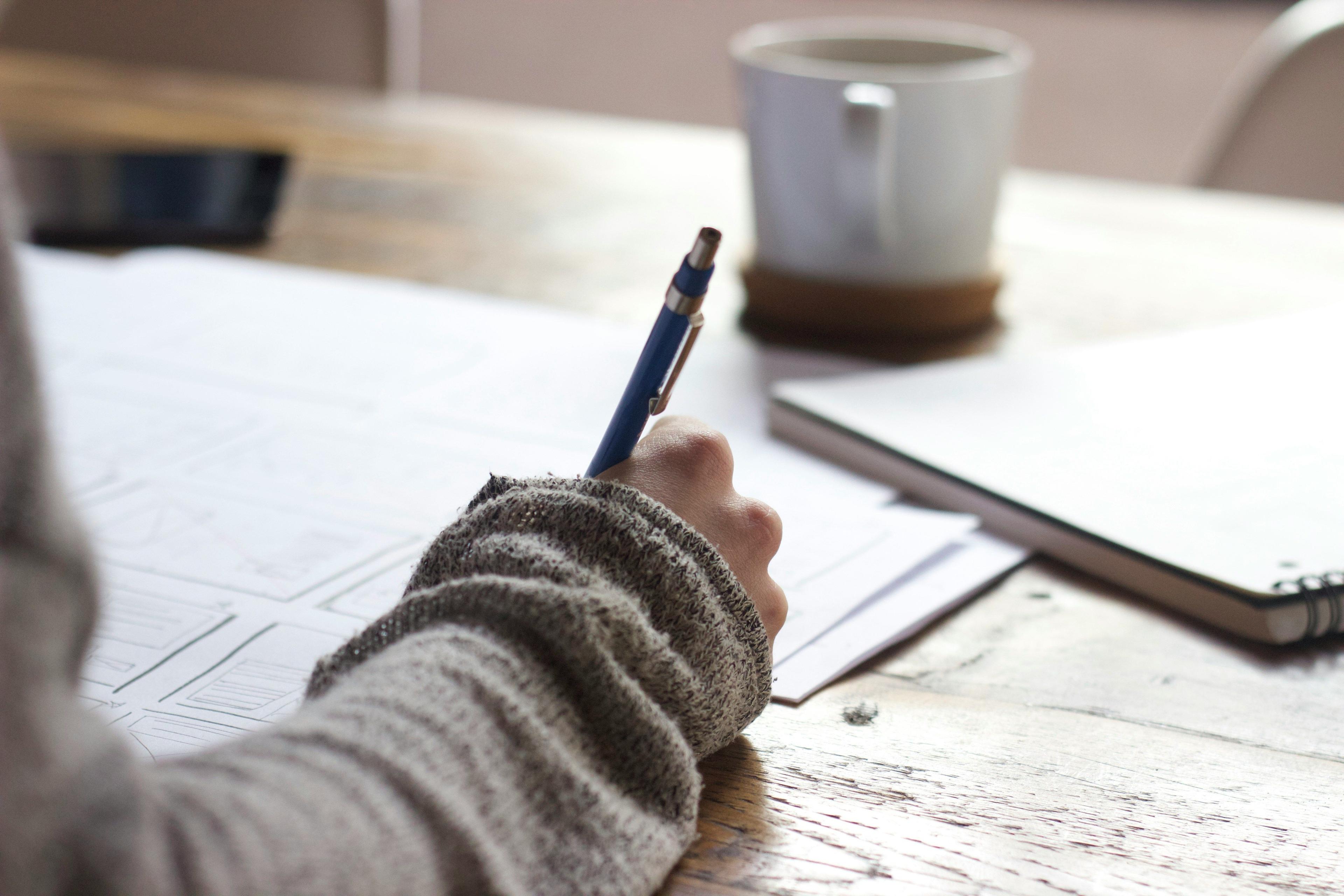 A person holding a pen and sketching some wireframes